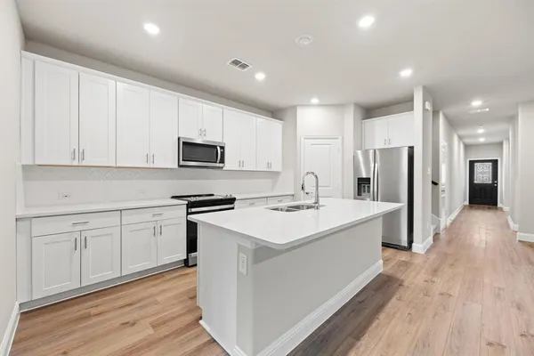 a kitchen with a sink a microwave a refrigerator and cabinets