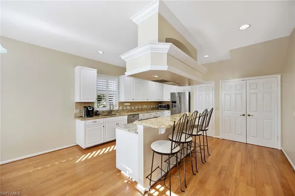 a kitchen with stainless steel appliances a white table chairs and a refrigerator
