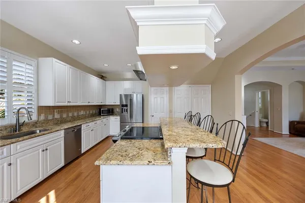 a kitchen with stainless steel appliances granite countertop a kitchen island hardwood floor sink stove dining table and chairs