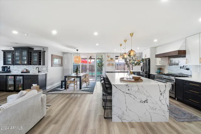 a kitchen with stainless steel appliances kitchen island granite countertop a stove top oven a sink a dining table and chairs