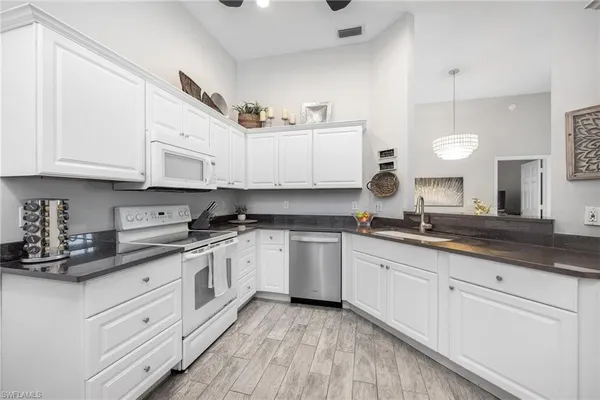 a kitchen with granite countertop white cabinets and white appliances