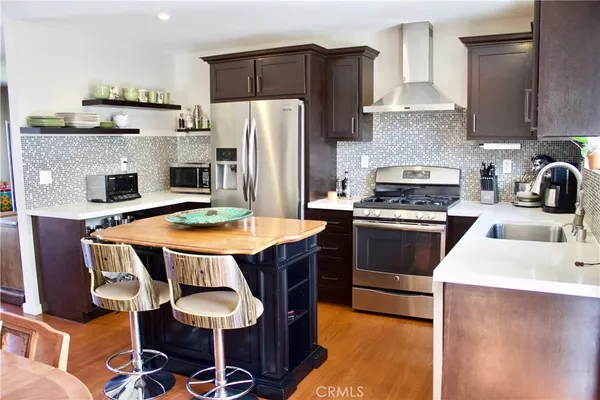 a kitchen with stainless steel appliances a dining table chairs stove refrigerator and sink