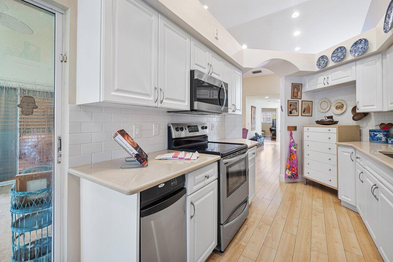 17266 Boca Club Boulevard, Unit 1603 Boca Raton, FL 33487 - Photo 15 of 42 a kitchen with stainless steel appliances granite countertop a sink dishwasher stove and white cabinets with wooden floor