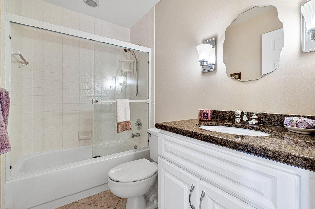 17266 Boca Club Boulevard, Unit 1603 Boca Raton, FL 33487 - Photo 29 of 42 a bathroom with a granite countertop sink a toilet a mirror and shower