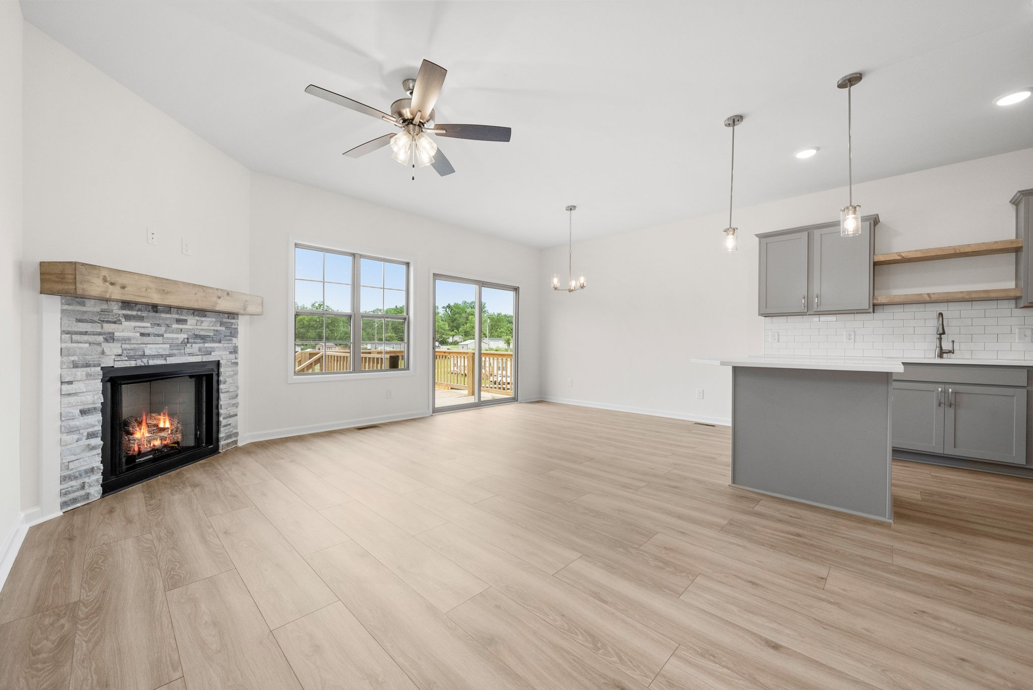 a view of an empty room with a fireplace and a ceiling fan