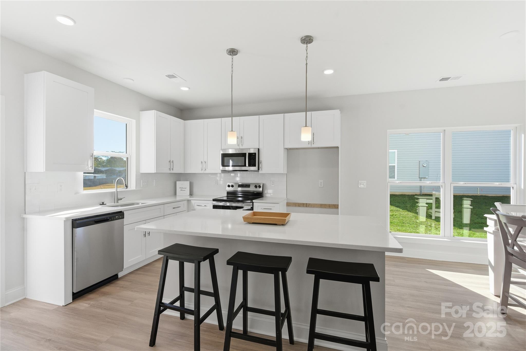 222 1st Street South Fort Mill, SC 29708 - Photo 11 of 23 a kitchen with stainless steel appliances granite countertop a stove a refrigerator a sink a stove and white cabinets with wooden floor