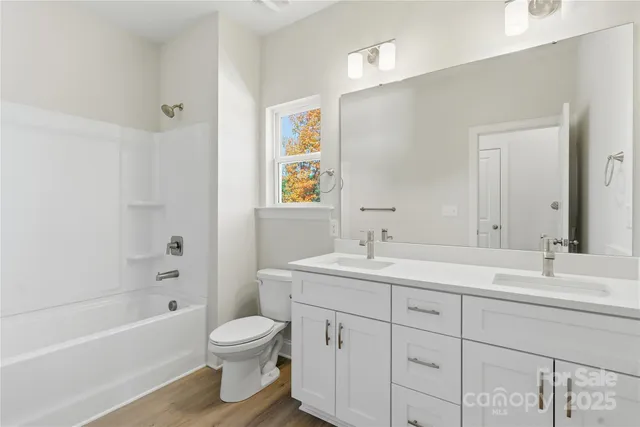 a bathroom with a toilet a sink a tub and mirror