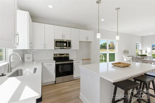 a kitchen with a sink a stove and chairs with wooden floor
