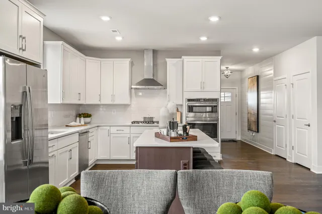 a kitchen with stainless steel appliances granite countertop a refrigerator a stove a sink dishwasher a oven with white cabinets and wooden floor