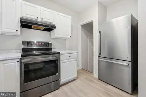 a kitchen with stainless steel appliances white cabinets white stove a refrigerator and a microwave