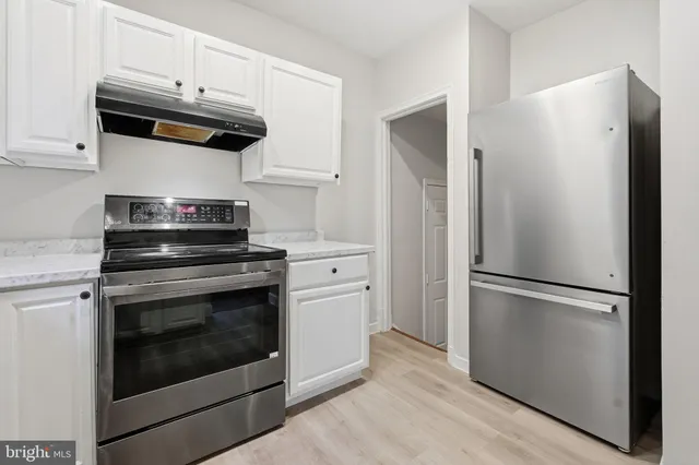 a kitchen with stainless steel appliances white cabinets white stove a refrigerator and a microwave