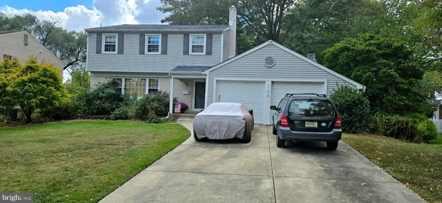 a front view of a house with a garden and trees