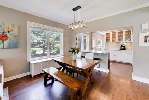 a dining room with wooden floor a chandelier a wooden table and chairs
