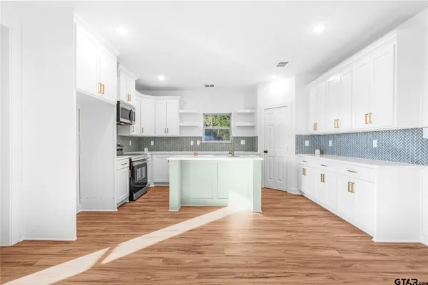 a large kitchen with kitchen island a sink a stove a refrigerator and white cabinets