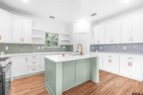 a kitchen with white cabinets sink and stove