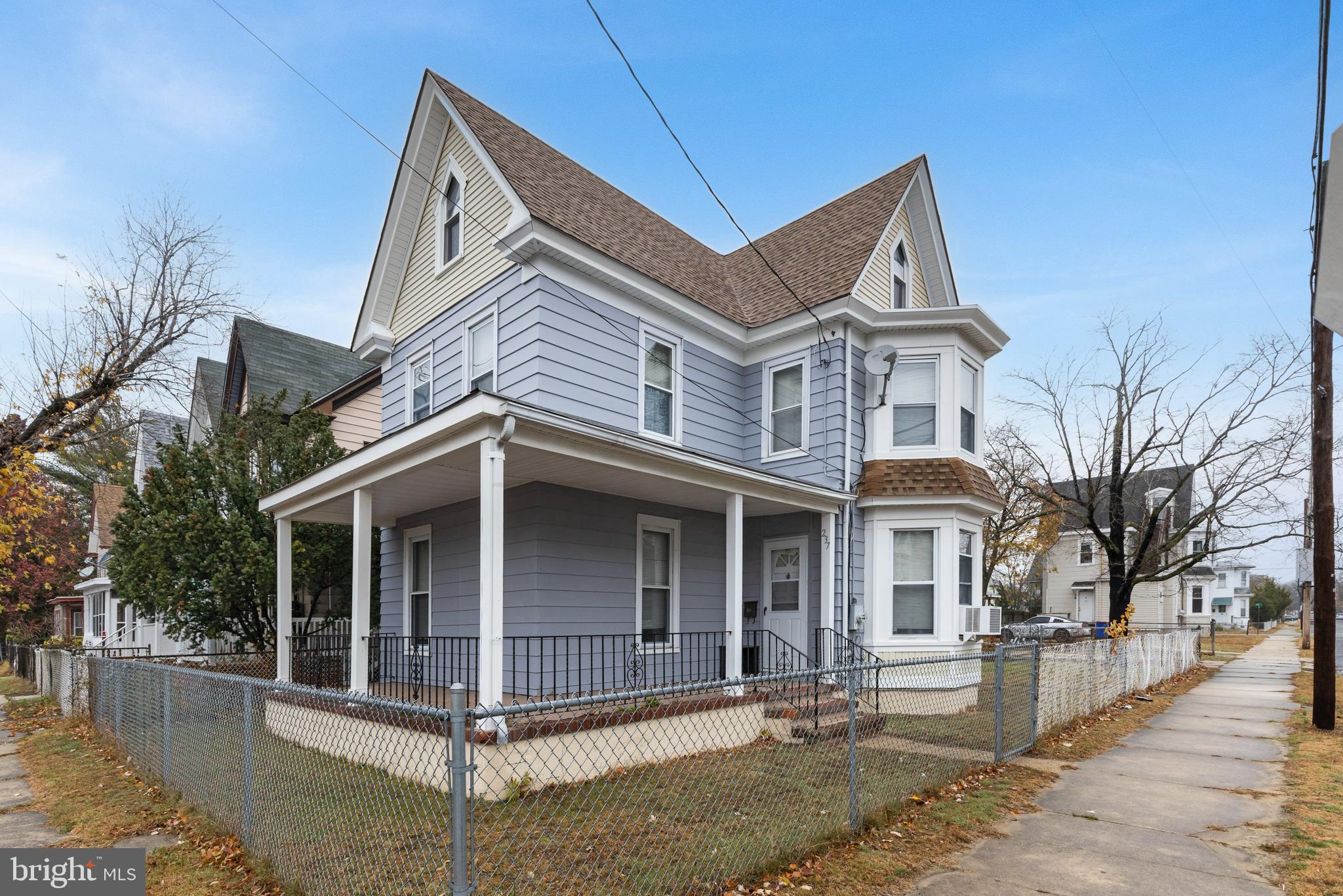a view of a white house with large windows and wooden fence
