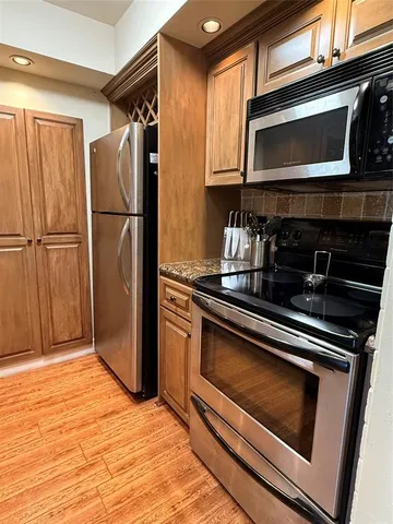a kitchen with granite countertop a refrigerator stove and microwave