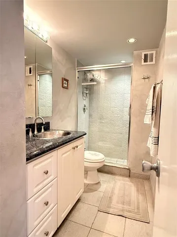 a bathroom with a granite countertop sink toilet and shower