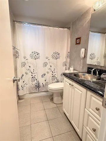 a bathroom with a granite countertop sink a toilet and a shower