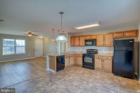 a kitchen with stainless steel appliances granite countertop a refrigerator a sink dishwasher a stove and a wooden cabinets