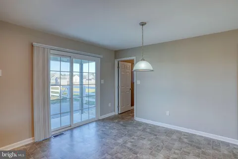 an empty room with chandelier fan and windows