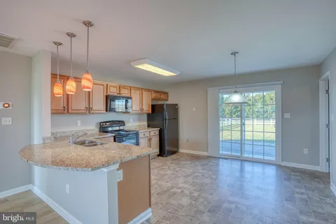 a kitchen with stainless steel appliances granite countertop a sink a stove a refrigerator a center island and a window