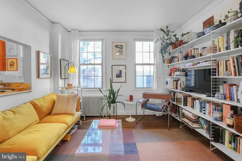 a living room with furniture a bookshelf and a window