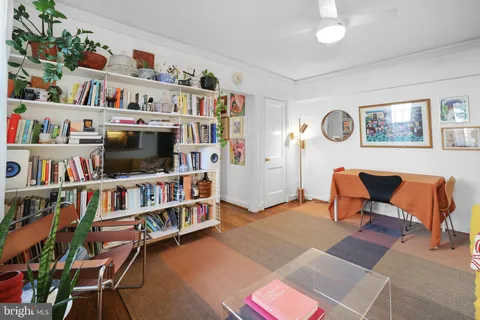 a living room with lots of books and a large window