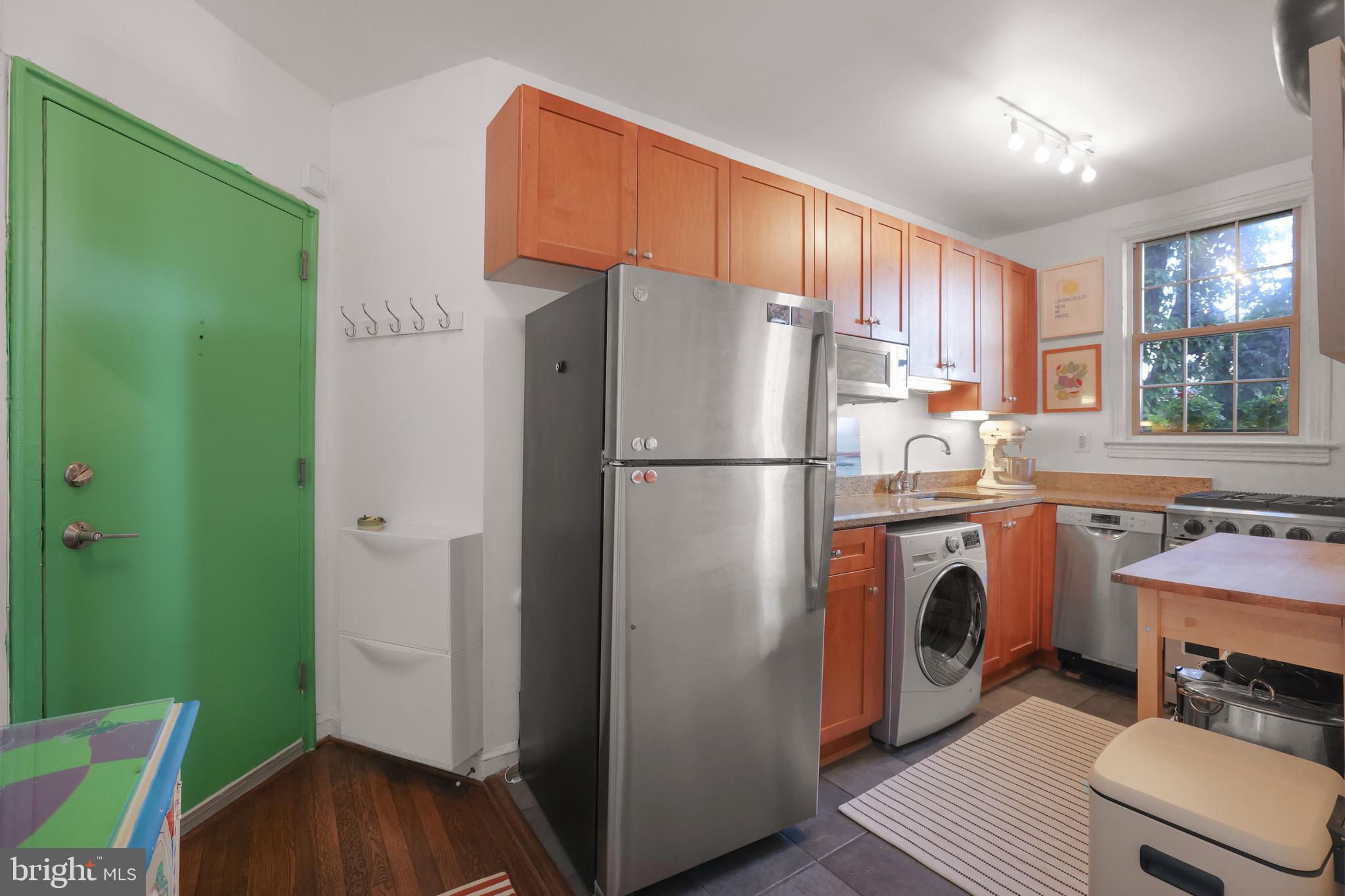 1441 Euclid Street Northwest, Unit 206 Washington, DC 20009 - Photo 8 of 19 a kitchen with stainless steel appliances a refrigerator a sink a stove a washer dryer and white cabinets