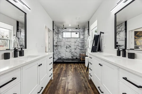 a bathroom with a granite countertop sink a mirror and shower