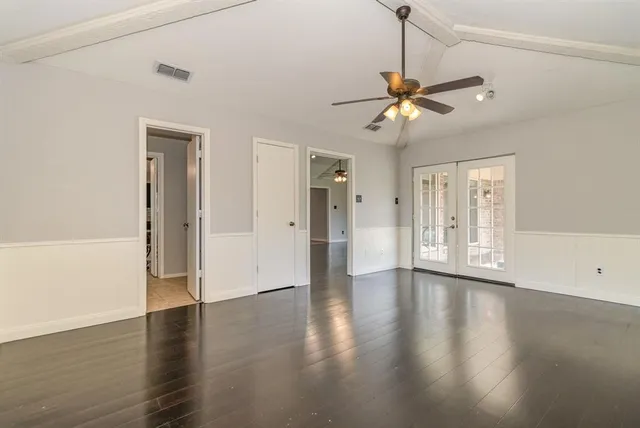 a view of a livingroom with wooden floor a ceiling fan and windows