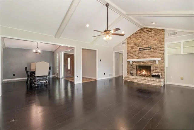 an empty room with wooden floor fireplace and dining table