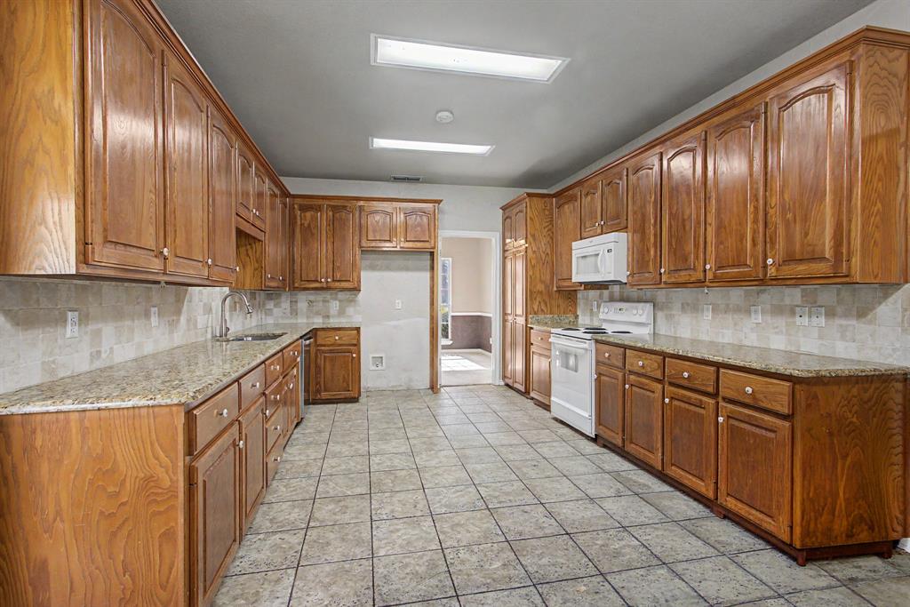 483 Christy Kay Lane Rhome, TX 76078 - Photo 13 of 40 a kitchen with stainless steel appliances granite countertop wooden cabinets a stove top oven a sink and dishwasher