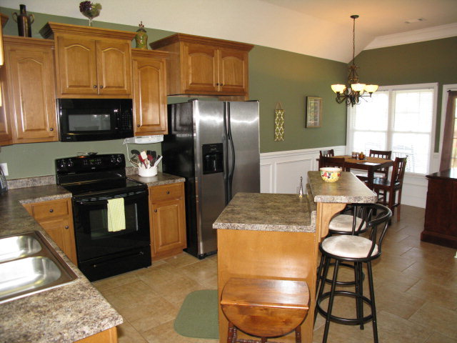 477 Bob White Road Macon, GA 31216 - Photo 7 of 21 a kitchen with stainless steel appliances granite countertop a stove a refrigerator a microwave a dining table and chairs with wooden floor