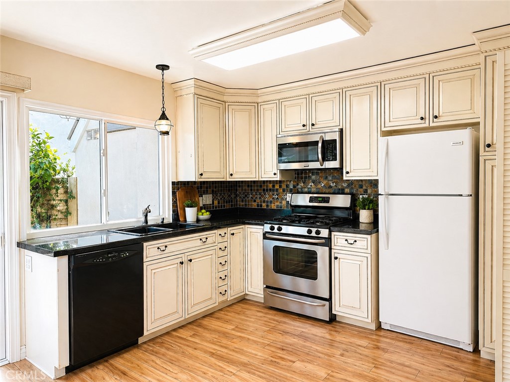 25 Brookfield Irvine, CA 92604 - Photo 7 of 17 a kitchen with granite countertop a refrigerator a stove a sink and white cabinets with wooden floor