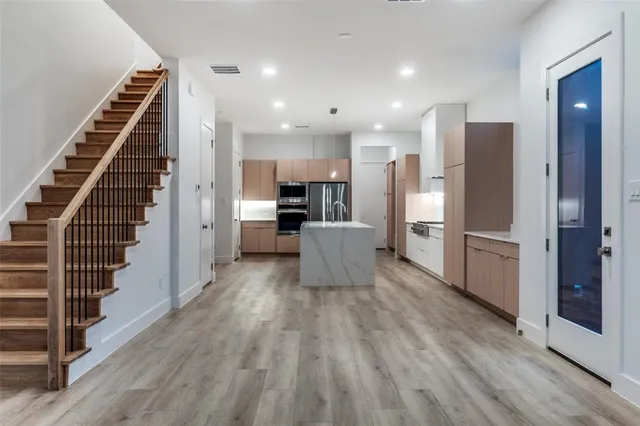 a room with stainless steel appliances kitchen island wooden floor and view living room