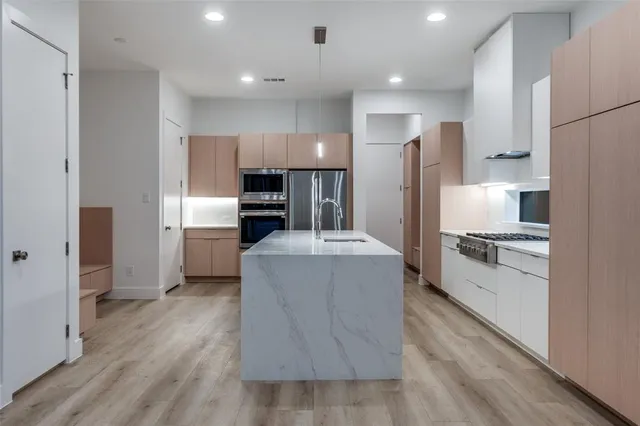 a large kitchen with a center island wooden floor stainless steel appliances and a window