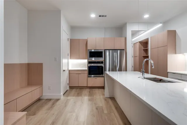 a kitchen with kitchen island a counter top space a sink stainless steel appliances and cabinets