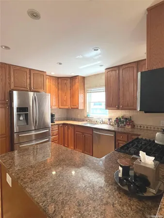 a kitchen with stainless steel appliances wooden cabinets a stove a sink and a refrigerator