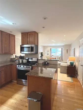 a kitchen with stainless steel appliances granite countertop a stove top oven a sink dishwasher a dining table and chairs with wooden floor