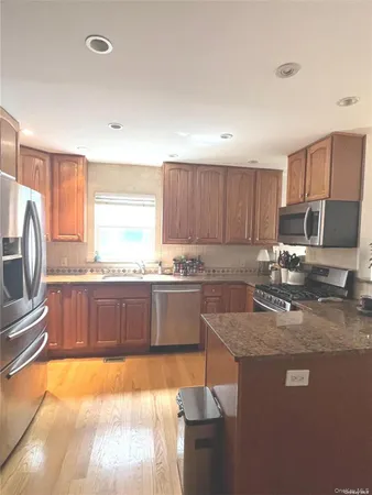 a large kitchen with granite countertop a sink refrigerator and cabinets