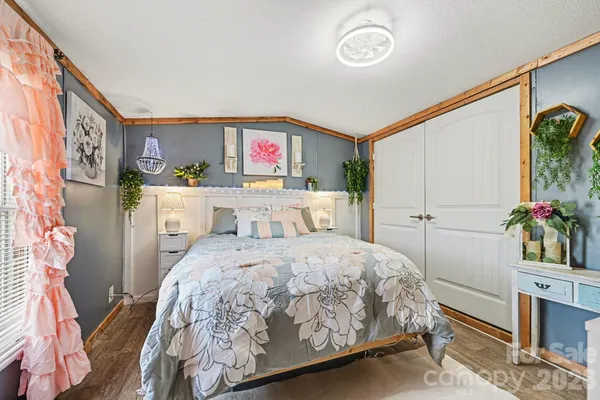 a bedroom with a bed and a potted plant on the dresser