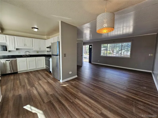 an open kitchen with wooden floor and stainless steel appliances
