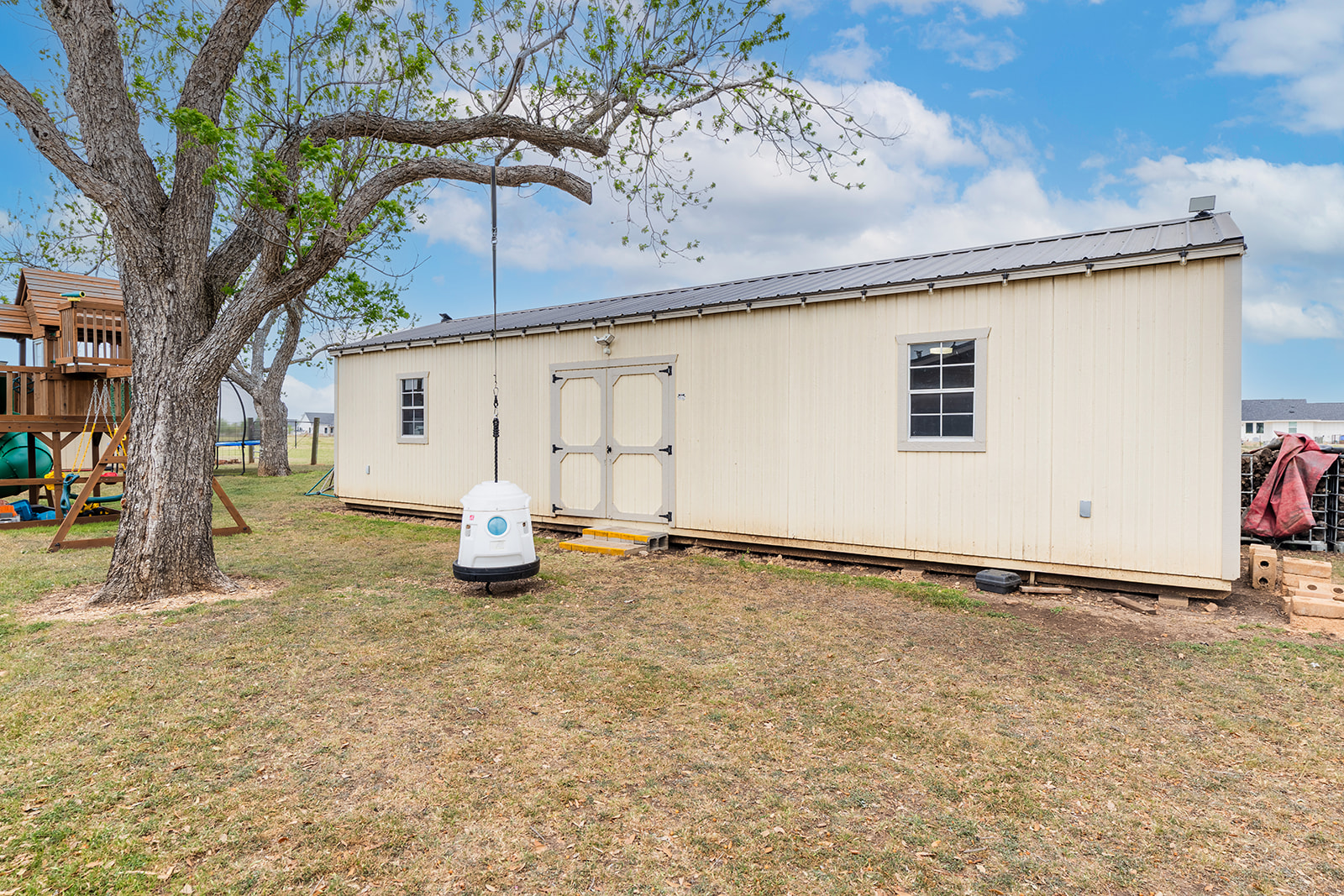 1001 Gravel Pit Road Taylor, TX 76574 - Photo 30 of 38 Rear view of house featuring a metal roof, a yard, an outdoor structure, a trampoline, and a playground