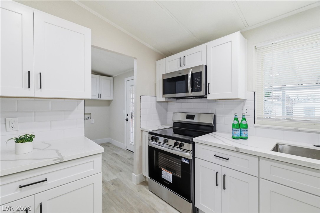 3940 Point Drive Pahrump, NV 89060 - Photo 17 of 35 A pristine kitchen offers modern white cabinetry, stainless steel appliances, and sleek countertops.