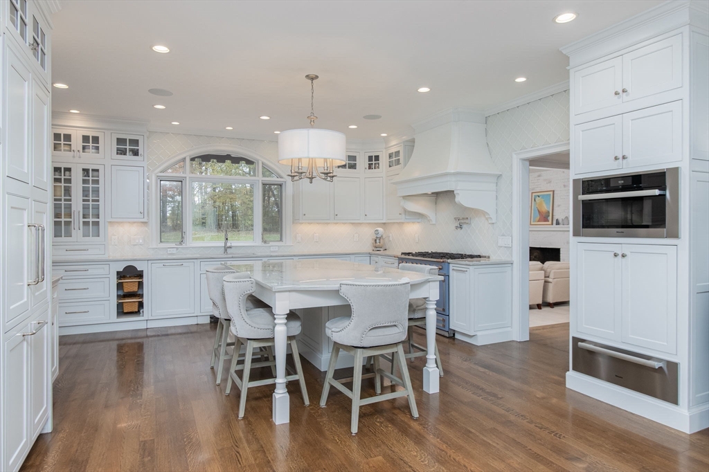 326 Old Ayer Road Groton, MA 01450 - Photo 5 of 42 a kitchen with stainless steel appliances kitchen island granite countertop a wooden floor and white cabinets
