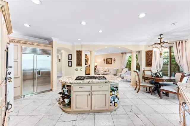 a room with stainless steel appliances kitchen island granite countertop a table and chairs in it