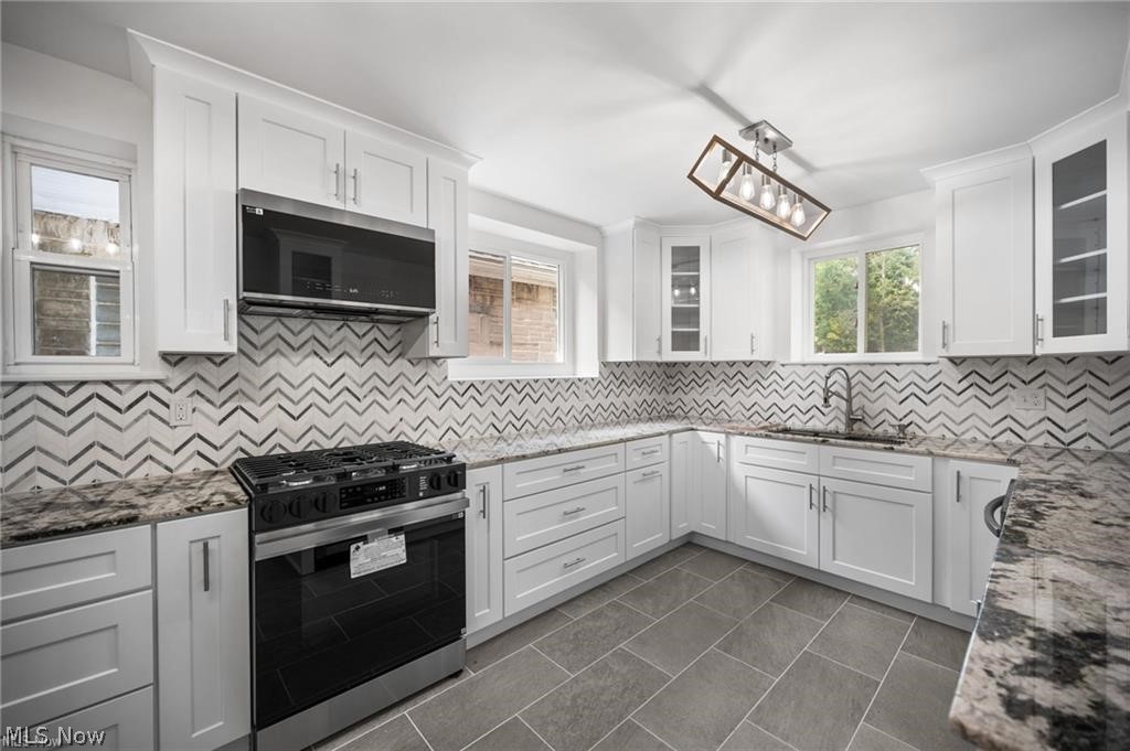 28300 Aurora Road Solon, OH 44139 - Photo 5 of 36 Kitchen featuring white shaker cabinetry, patterned tile backsplash, granite countertops, stainless steel appliances, and tile flooring