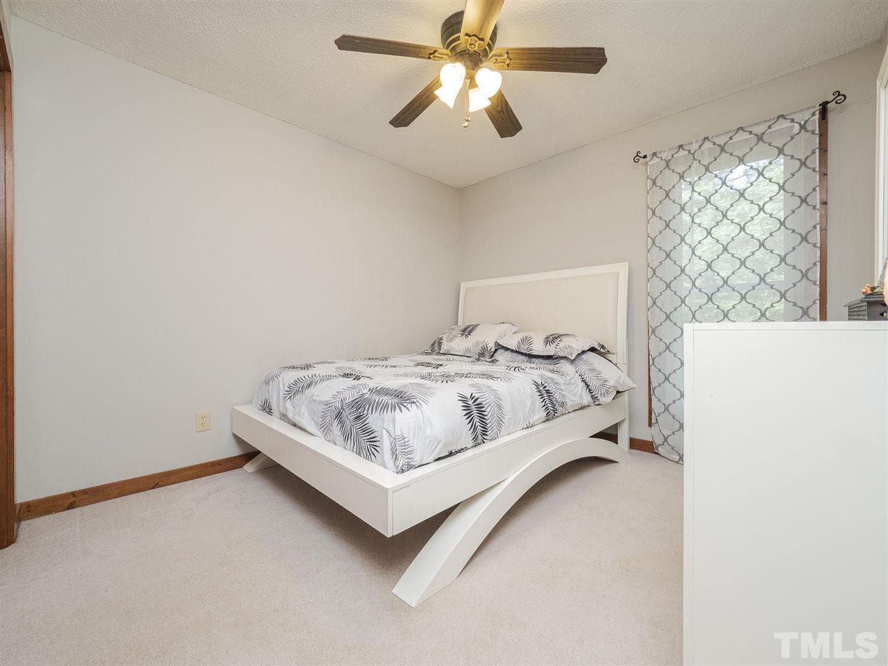 7220 Bluffside Court Raleigh, NC 27615 - Photo 14 of 23 a bedroom with a bed and a chandelier