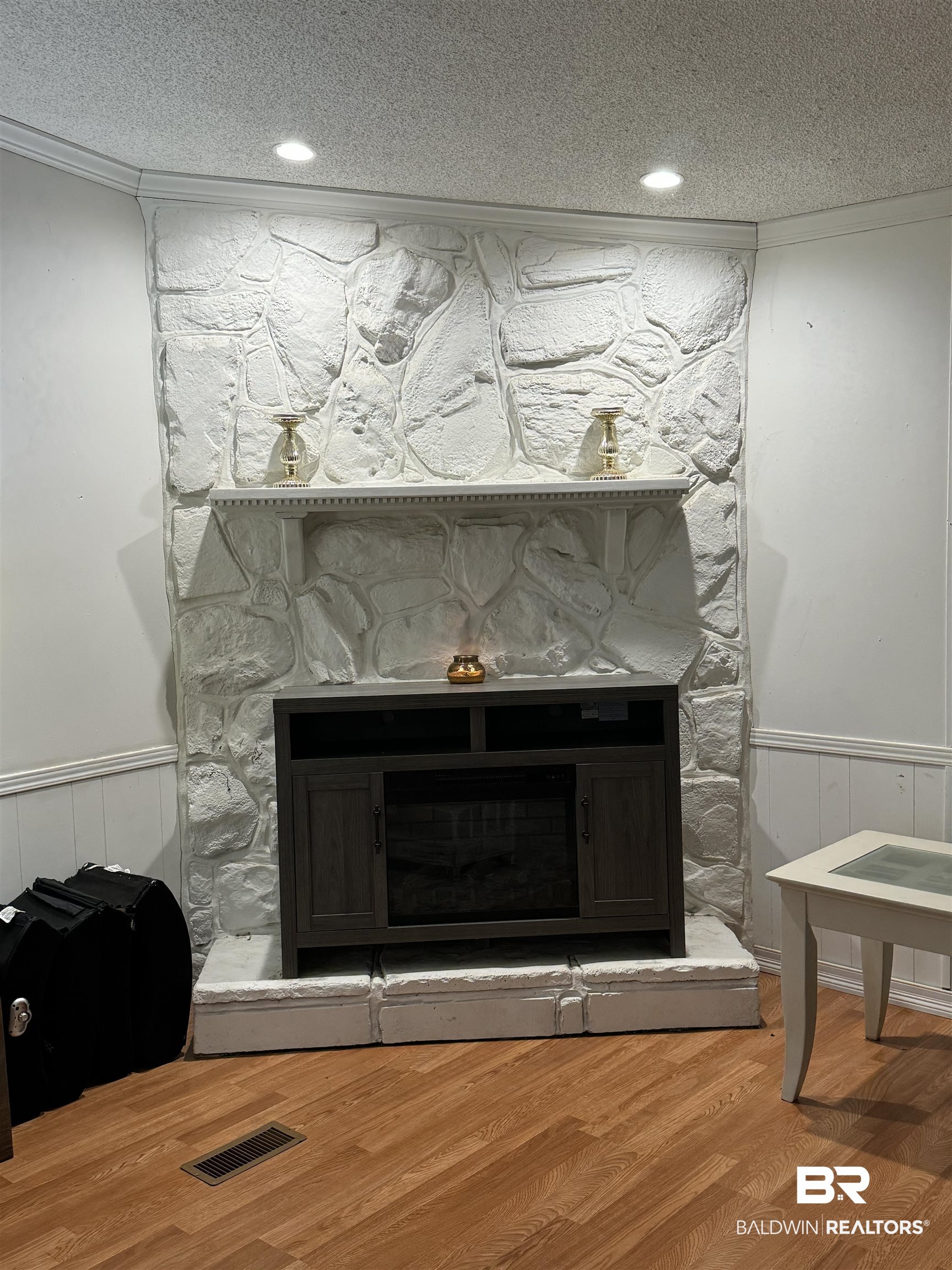 51235 Phillipsville Road Bay Minette, AL 36507 - Photo 24 of 63 Detailed view of a wainscoted wall, a fireplace, a textured ceiling, a decorative wall, and crown molding
